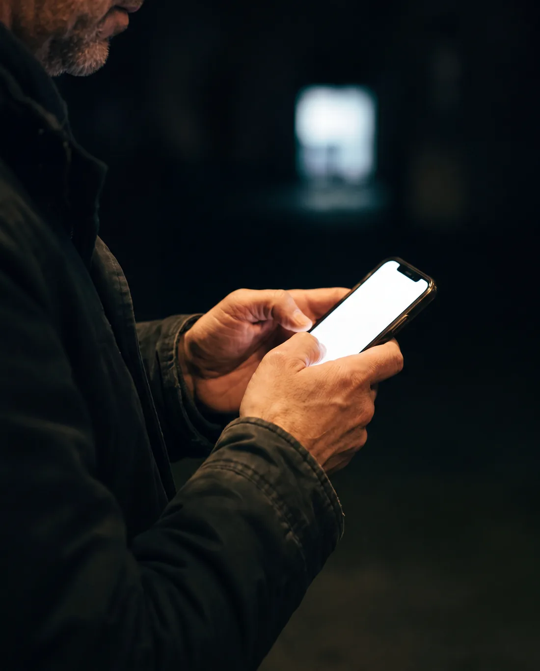 A phone held in a dark room, one clean answer lighting the hands